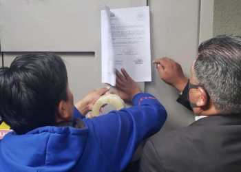 Los funcionarios de la ALP pegan la notificación en la Casa Grande del Pueblo. (Prensa Senado)