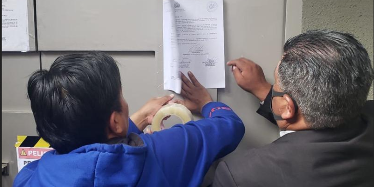 Los funcionarios de la ALP pegan la notificación en la Casa Grande del Pueblo. (Prensa Senado)