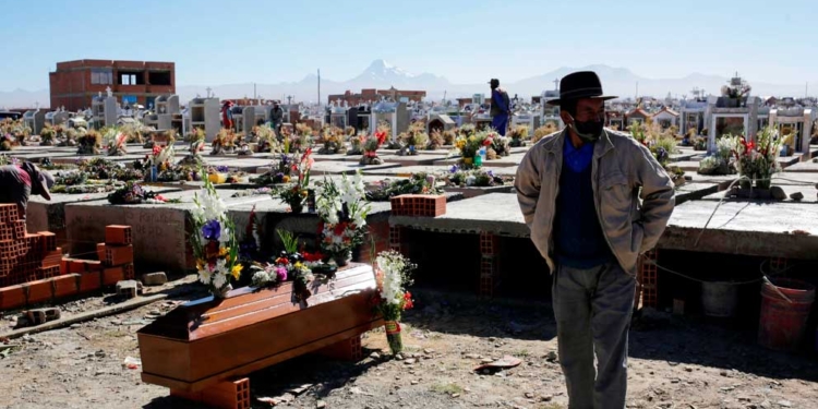 Un hombre junto al ataúd de un pariente en un cementerio en las afueras de La Paz. Credit...David Mercado/Reuters