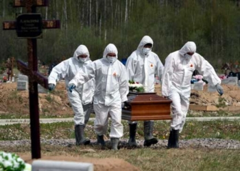 Enterradores con trajes de protección cargan el ataúd de una víctima del COVID-19 en una sección de cementerio reservada para fallecimientos por el nuevo coronavirus en Kolpino, a las afueras de San Petersburgo, Rusia.(ASSOCIATED PRESS)