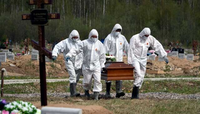 Enterradores con trajes de protección cargan el ataúd de una víctima del COVID-19 en una sección de cementerio reservada para fallecimientos por el nuevo coronavirus en Kolpino, a las afueras de San Petersburgo, Rusia.(ASSOCIATED PRESS)